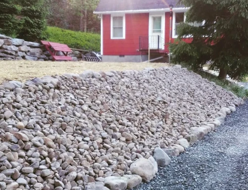 Decorative river rock landscape bed installed across a residential front yard