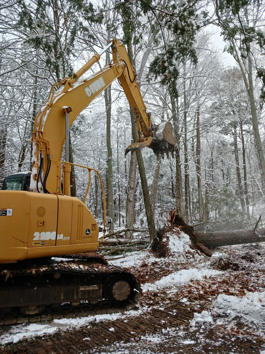 John Deere excavator clearing a snowy wooded lot in Northeast PA