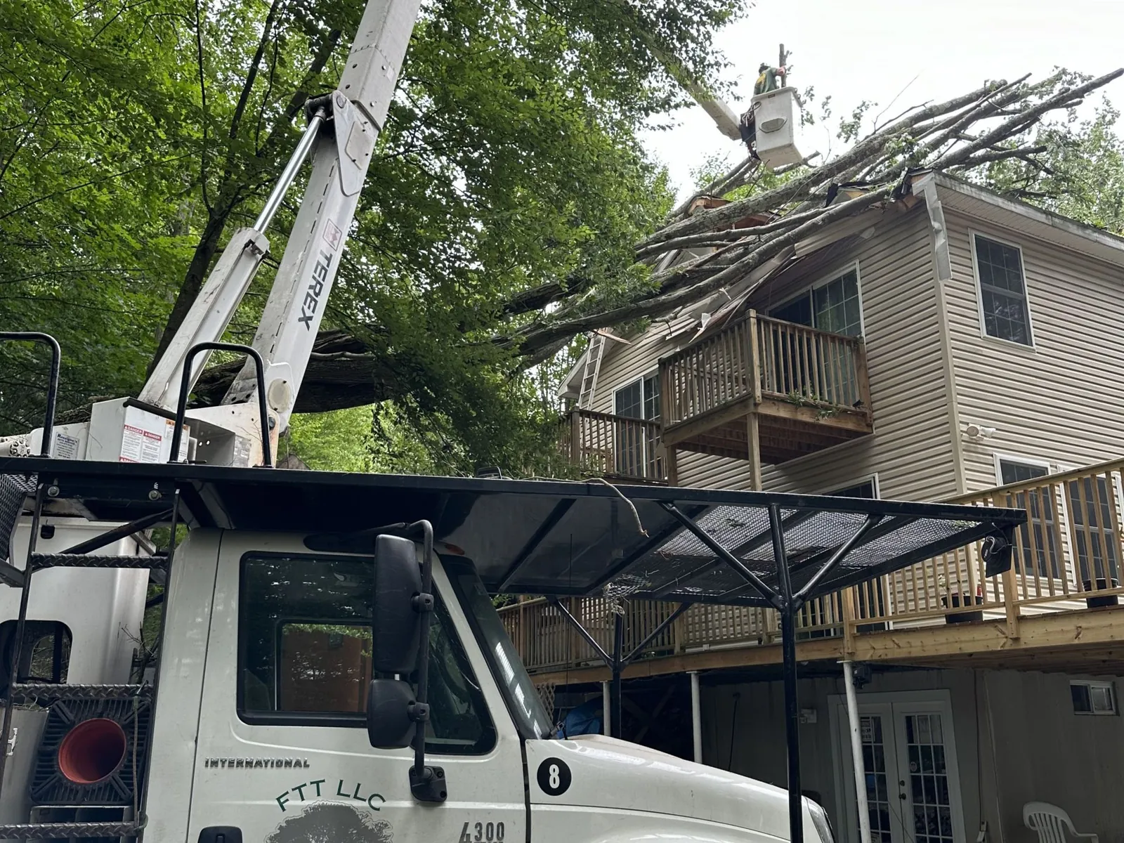 Bucket truck removing a fallen tree from a home